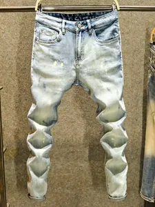 Jean slim dégradé bleu clair pour homme avec détails usés et taches de peinture.