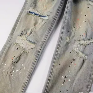 Close-up of men's retro wash distressed jeans with ripped details and paint splatter.