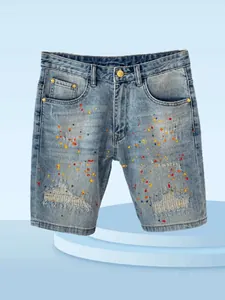 Close-up of men's slim fit denim shorts with colorful paint splatter and distressed details