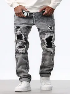 Detail shot of men's grey distressed jeans featuring heavy knee rips and black patches