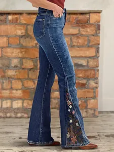 Women's high-waisted dark blue flare jeans with elegant floral side embroidery detail