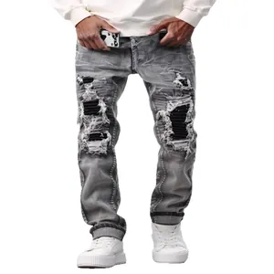Detailed view of men's high street grey ripped jeans with black patches and frayed edges