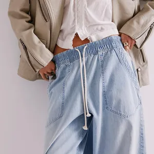Detailed close-up of light blue washed denim pants with elastic drawstring waist.