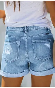 Detailed view of women's light blue distressed denim shorts with ripped back pockets