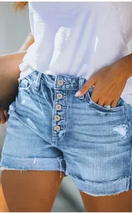 Close-up of distressed blue denim shorts with button-fly and pocket detail.