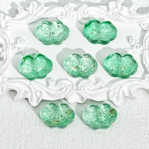 Detailed macro shot of green Ruyi cloud-shaped glass beads with gold foil for jewelry
