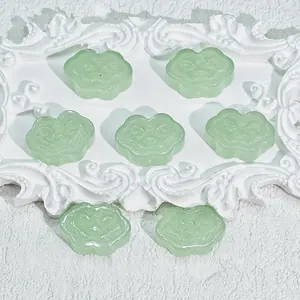 Macro detail of pale green Ruyi cloud-shaped glass beads for DIY jewelry accessories