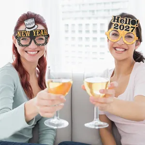 Two women wearing festive 2027 New Year party glasses and toasting with wine glasses