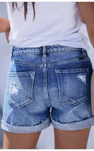Detailed view of women's distressed denim shorts back pockets with ripped style