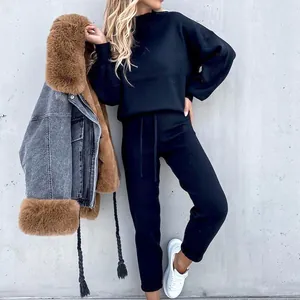 Primo piano della vestibilità del set nero con felpa a collo alto e pantaloni.