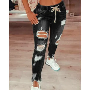 Gros plan sur la texture denim déchirée d'un jean skinny noir à cordon de serrage