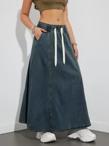 Close-up of a denim maxi skirt with an elastic drawstring waist and side pockets.