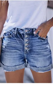 Detailed macro shot of high-waisted distressed denim shorts featuring a button-up fly