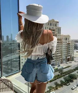 Rear view of high waisted umbrella denim shorts worn by a model on a sunny balcony