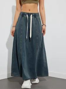 Detail view of a long denim skirt featuring an elastic waist and white drawstrings.