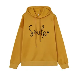 Detalle de sudadera con capucha mostaza con estampado Smile y corazón negro