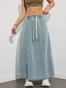 Detail of light blue denim maxi skirt with elastic drawstring waistband and A-line silhouette.