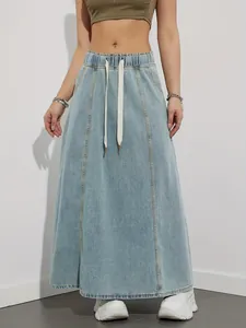 Detail of light blue denim maxi skirt with elastic drawstring waist and flowy hem.