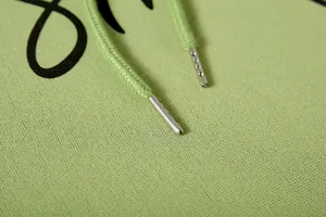 Detalle de cerca del cordón de la sudadera con capucha verde claro con puntas de metal plateado