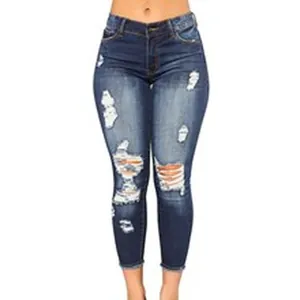 Close-up view of dark blue distressed skinny jeans with ripped knee and frayed hem details