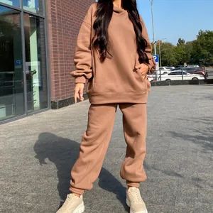 Detail shot of a brown oversized hooded tracksuit worn in an outdoor urban setting