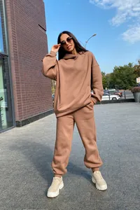 Stylish women's oversized tan hoodie and matching jogger two-piece loungewear set in urban setting
