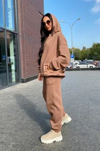 Model wearing a stylish brown oversized two-piece hoodie and sweatpants set outdoors