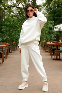Woman wearing a white hooded sweatshirt and joggers set in an outdoor cafe setting