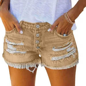 Close-up detail of women's distressed tan denim shorts with frayed hem and multi-button fly
