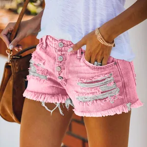 Detail of distressed pink denim shorts featuring fringe hem and a multi-button fly design