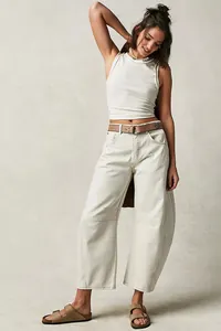 Detail view of women's loose wide-leg barrel jeans in off-white washed denim fabric