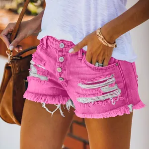 Detail view of pink distressed denim shorts featuring button fly and frayed hem design