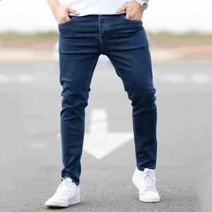 Gros plan d'un jean en denim extensible bleu foncé à la mode pour hommes sur un modèle.