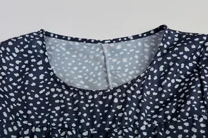 Detailansicht des runden Ausschnitts und des geometrischen Musters an einem blauen Kleid.