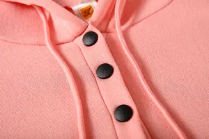 Detailed macro shot of a pink sweatshirt collar featuring black buttons and drawstrings