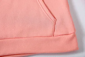 Macro detail of soft pink hoodie fabric showing pocket seam and ribbed hemline