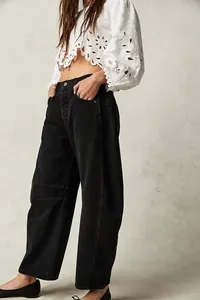 Dettaglio di jeans neri a gamba larga lavati abbinati a un top corto bianco ricamato