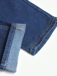 Gros plan montrant les coutures de haute qualité et l'ourlet du jean bleu en denim stretch.