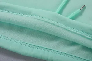 Nahaufnahme von mintgrünem Hoodie-Stoff mit weichem Fleecefutter und Kordelzugdetail