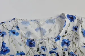 Nahaufnahme des Ausschnitts eines Kleides mit blauem Blumenmuster und feiner Textur