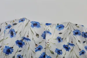Detailaufnahme von blauem Kornblumenmuster und Rundhalsausschnitt am weißen Kleid
