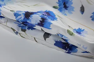 Nahaufnahme zeigt lebendigen blauen Blumendruck und feine Stofftextur auf dem weißen Herbstkleid