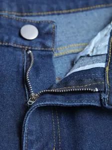 Détail d'une fermeture éclair en métal sur un jean bleu extensible de haute qualité