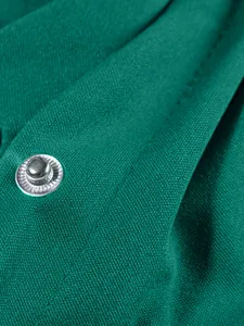 Dettaglio macro del tessuto verde e del bottone automatico in metallo sulla giacca