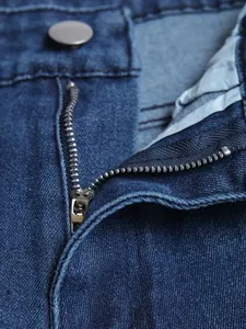 Close-up detail of a durable metal zipper fly on blue slim fit men's stretch denim jeans