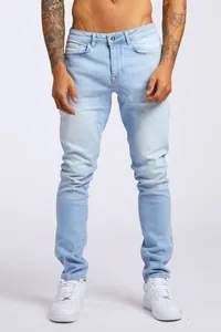 Jean en denim bleu clair pour hommes coupe ajustée avec baskets blanches en studio
