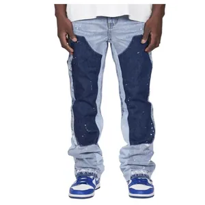 Front view detail of men's blue patchwork stacked flare jeans with paint splatters.
