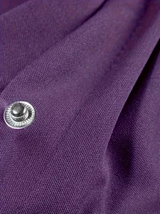 Close-up detail of purple sports jacket fabric texture and silver metal snap button