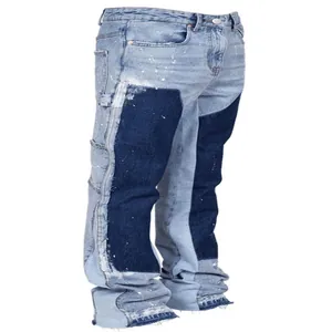 Side view of men's stacked flared denim jeans with dark blue patchwork and paint splatters