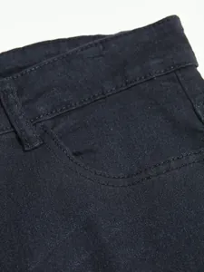 Macro close-up view of black denim jeans fabric showing pocket detail and stitching quality